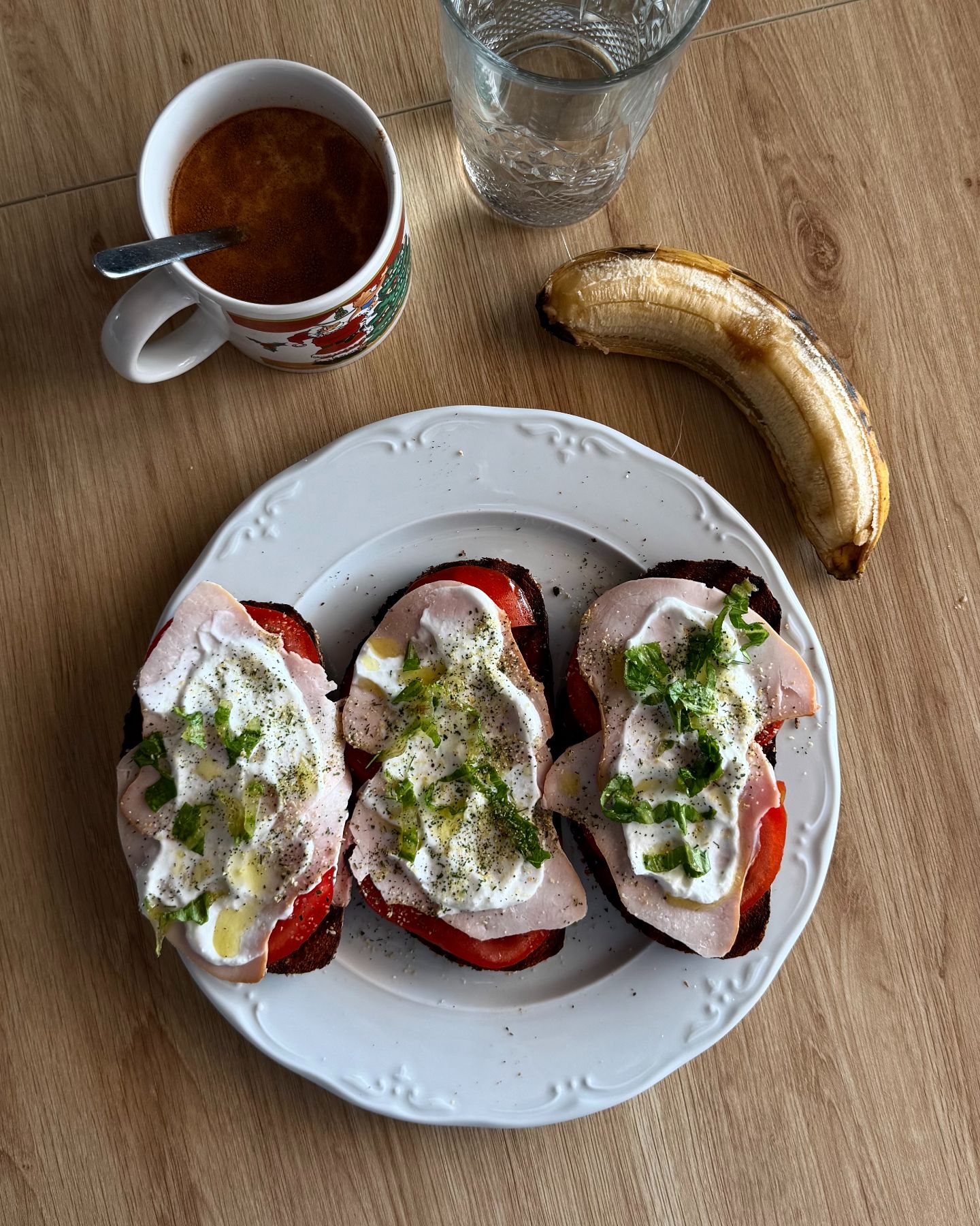 Desayuno de tostadas con jamón y tomate, café y plátano.